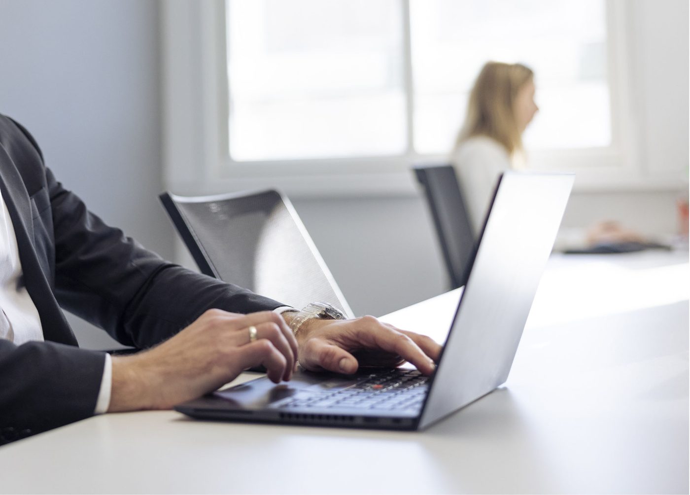 A person sitting a desk typing on a laptop.