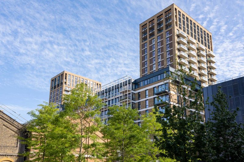 Modern apartment buildings and trees under a blue sky.