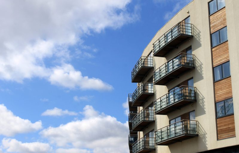 Modern apartment building exterior with balconies against a blue sky.