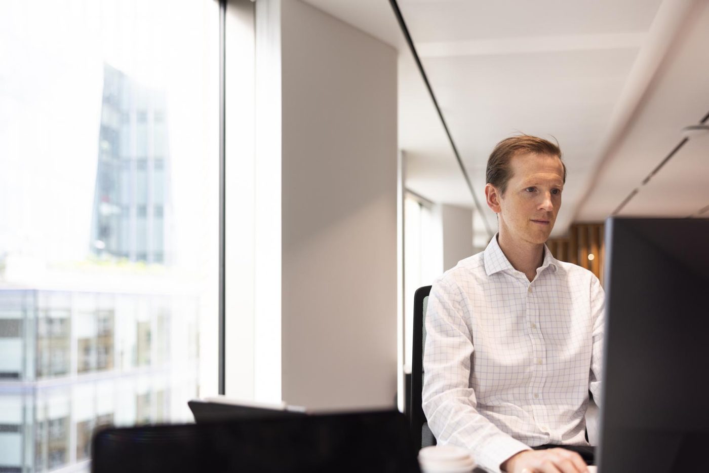 Modern office interior; man working at computer.