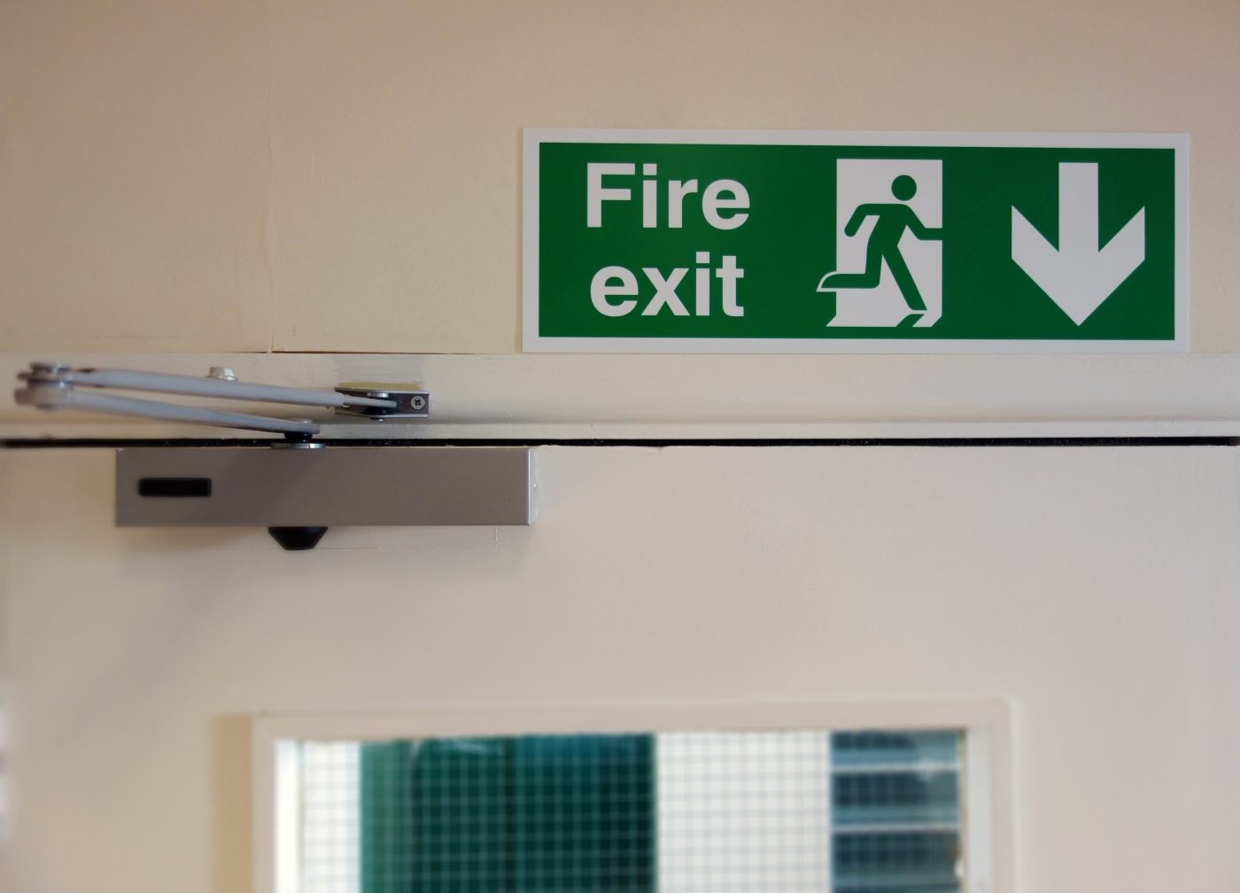 Green fire exit sign above a door; downward arrow.