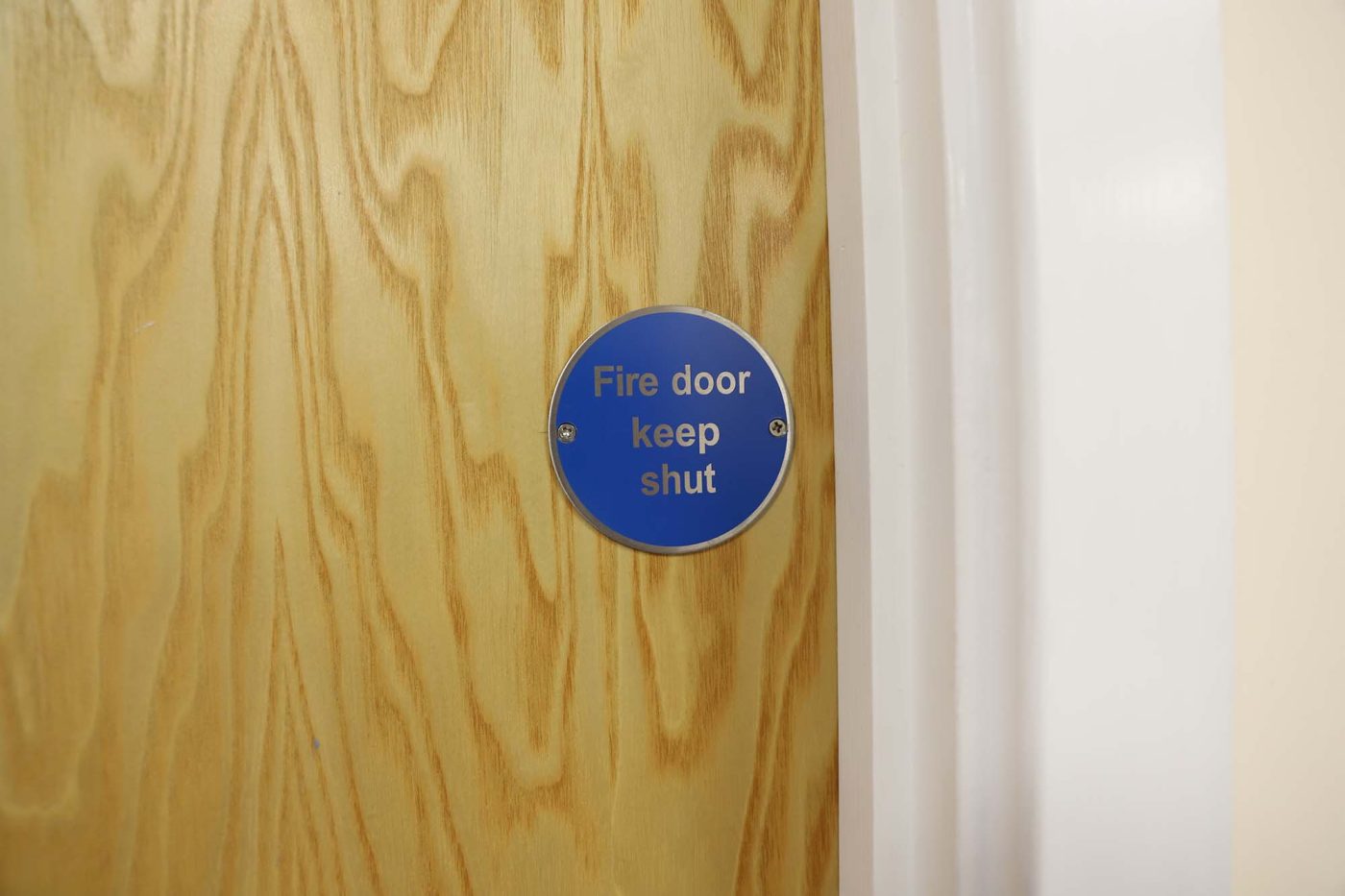 Blue sign on wood door: "Fire door keep shut"