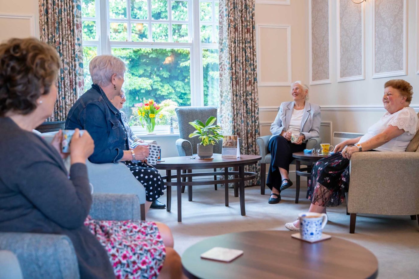 Senior women enjoying tea and conversation in a comfortable lounge.