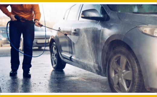 Person pressure washing a car.