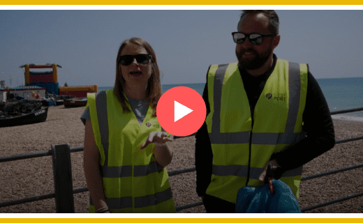 Two people in high-vis vests at a beach cleanup.