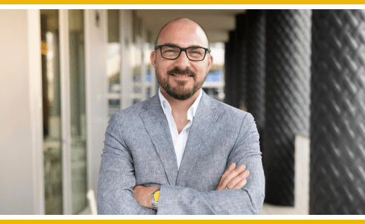 Portrait of a man in a gray blazer, arms crossed.