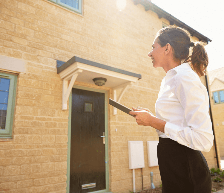 Woman holding tablet outside house.