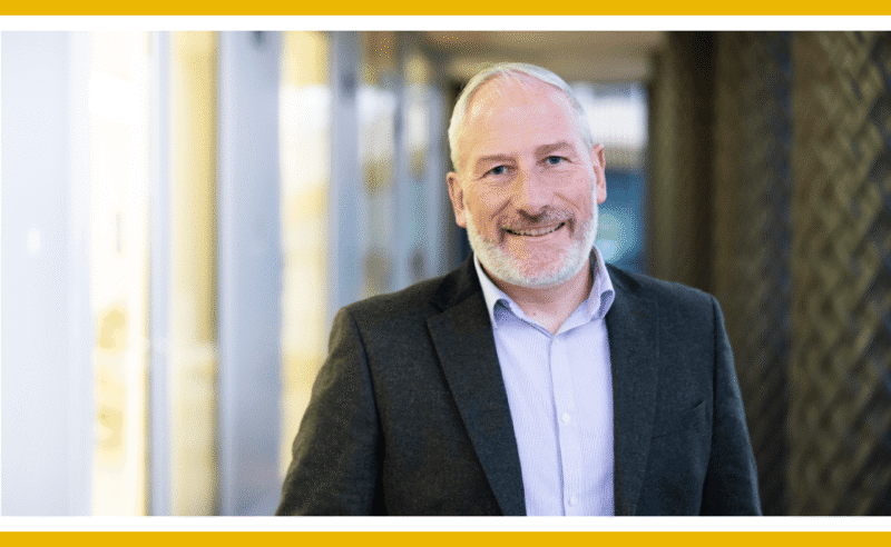 Smiling man in a suit jacket.