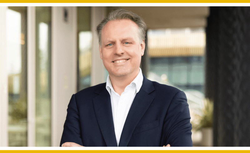 Smiling man in suit, arms crossed.