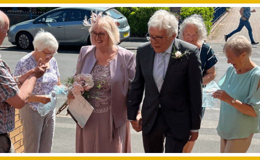Couple celebrating their wedding, surrounded by guests.