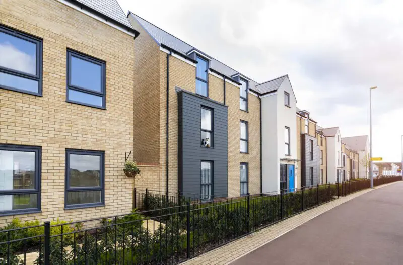 Row of new homes with black fences and paved walkway.