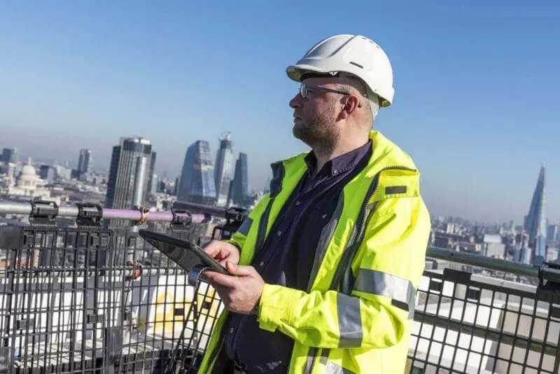 Architect using tablet overlooking London skyline.